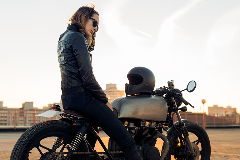 mulher em cima da moto com o capacete apoiado no tanque de gasolina